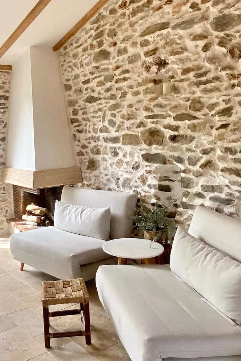 Salon chaleureux à Craponne-sur-Arzon — cheminée à foyer ouvert, linteau en chêne massif, mur de pierre rejointoyé à la chaux